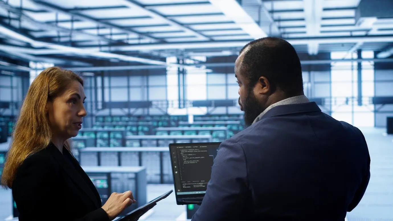 Сотрудники дата-центра проводят ежегодное обслуживание, используя ноутбук и планшет.